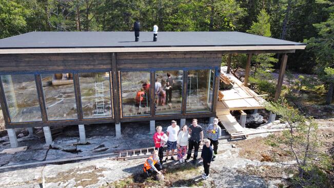 Veera ja Wilhelm Gustafssonin (keskellä) mökki on rakennettu isän ja pojan yhteistyöllä, mutta myös talkoovoimalla. Wilhelmin äiti on hoitanut paljon kohta viiden kuukauden ikäistä vauvaa, joka syntyi päivää ennen mökkipaketin saapumista tontille. 