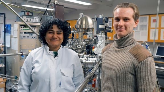 Zahra ”Elmira” Jahanshah Rad ja Mikko Miettinen fysiikan materiaalitutkimuksen laboratoriossa, jossa he ovat kehitt&#228;neet patentoidut keksint&#246;ns&#228;. Taustalla ultrasuurtyhji&#246;laitteisto, joka mahdollistaa puolijohteiden k&#228;sittelyn ja mittaamisen puhtaassa ymp&#228;rist&#246;ss&#228;.  
