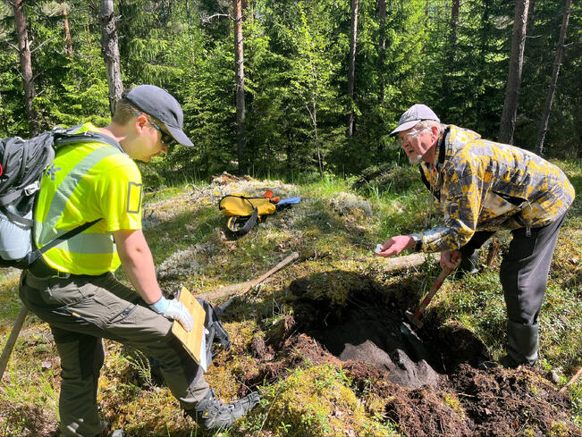 Korkeakouluharjoittelija Tuomas Heikkinen tutkii tunnustuspalkinnon voittaneen Veli-Matti Koivulan kanssa kuparipitoista gneissikalliota.