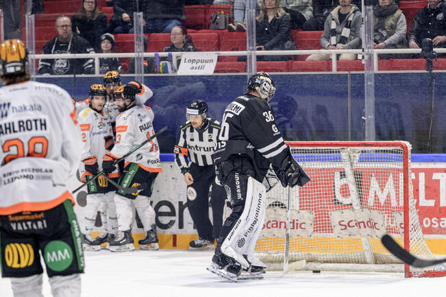 TPS:n maalivahti Eetu Mäkiniemi joutuu kaivamaan kiekon maalistaan HPK:n pelaajien juhliessa.